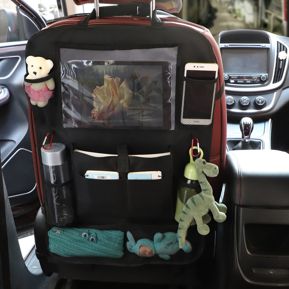 Black Oxford fabric car back seat organizer strapped to a seat holding a tablet and toys; contents and seat not included.