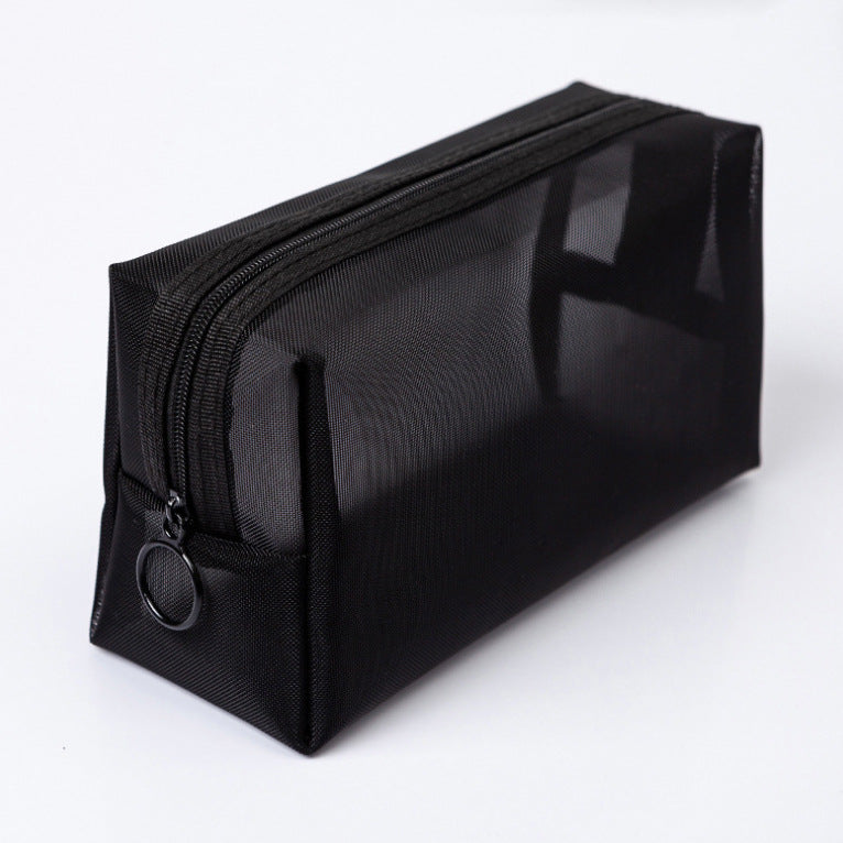 Black nylon mesh travel pouch lying diagonally on a white surface, shown on its own.