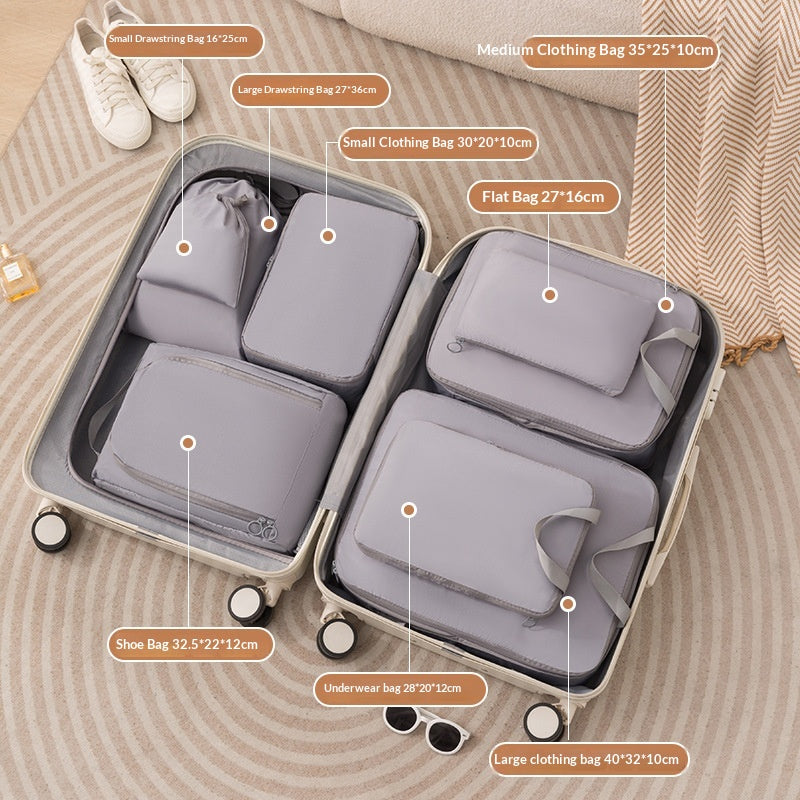 Grey fabric packing cubes fitted in a suitcase beside shoes and sunglasses on a rug; suitcase and accessories not included.