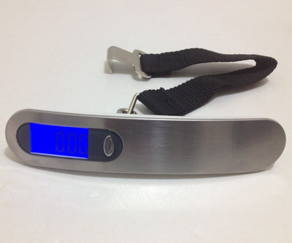 Silver and black digital luggage scale lying flat on a white surface with its readout visible for a pre-flight weight check.