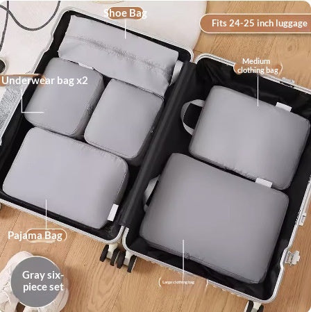 Grey nylon packing cubes packed inside an open suitcase on a wooden floor; suitcase and shoes not included.